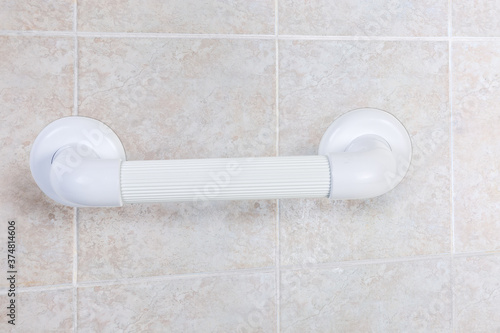 Plastic grab bar mounted on wall with tiles, close-up
