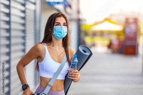 Woman trying to do sport during coronavirus crises despairing of the world. Portrait of a woman exercising wearing a facemask and holding a yoga mat - COVID-19 pandemic lifestyle concepts © Dragana Gordic
