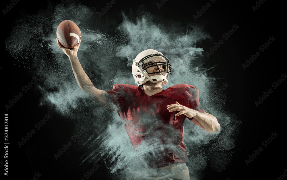 American football sportsman player with ball in action on stadium under lights of background. Sport, proud footballer in white helmet and red t-shirt ready to play.