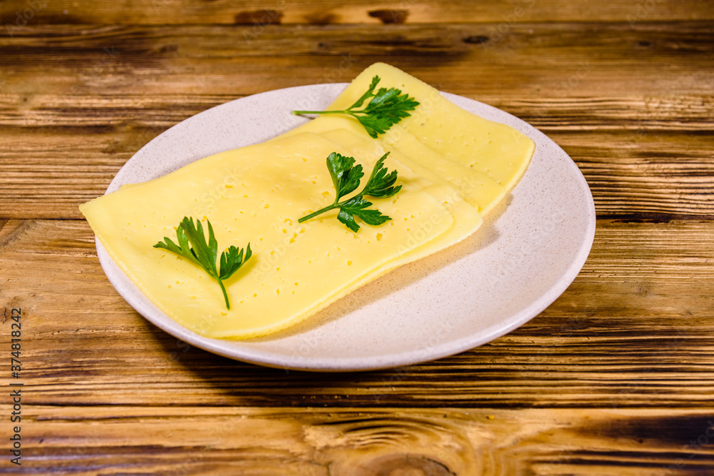 Sliced cheese and parsley in ceramic plate on wooden table Sliced cheese and parsley in ceramic plate on wooden table