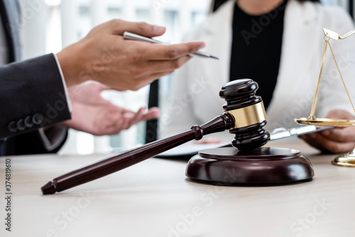 A male lawyer or a judge counseling clients about judicial justice and prosecution with scales, judges gavel, legal documents legal services concept