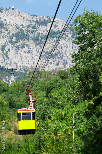 yellow cabin moves up cable car over cliffs © sommersby