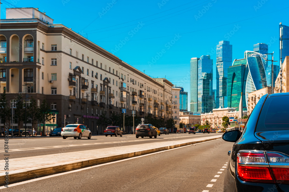 Glass skyscrapers in a business district in Moscow photographed from a city street behind parked cars