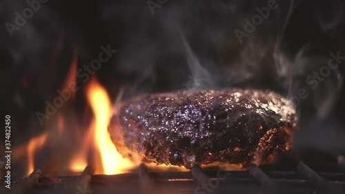 juicy beef Burger Patty is grilled over a high heat on the grate grill in sparks of ash and flame. cooking a hamburger on a picnic outside. Delicious BBQ grill Burger. preparation of food on BBQ grill