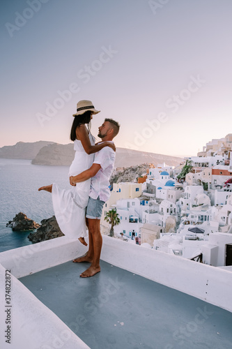 Santorini Greece, young couple on luxury vacation at the Island of Santorini watching sunrise by the blue dome church and whitewashed village of Oia Santorini Greece . Europe photo