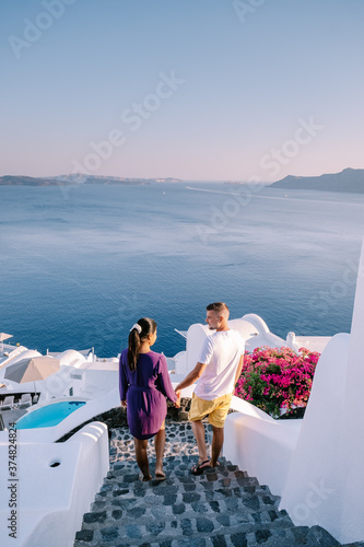 Santorini Greece, young couple on luxury vacation at the Island of Santorini watching sunrise by the blue dome church and whitewashed village of Oia Santorini Greece . Europe photo