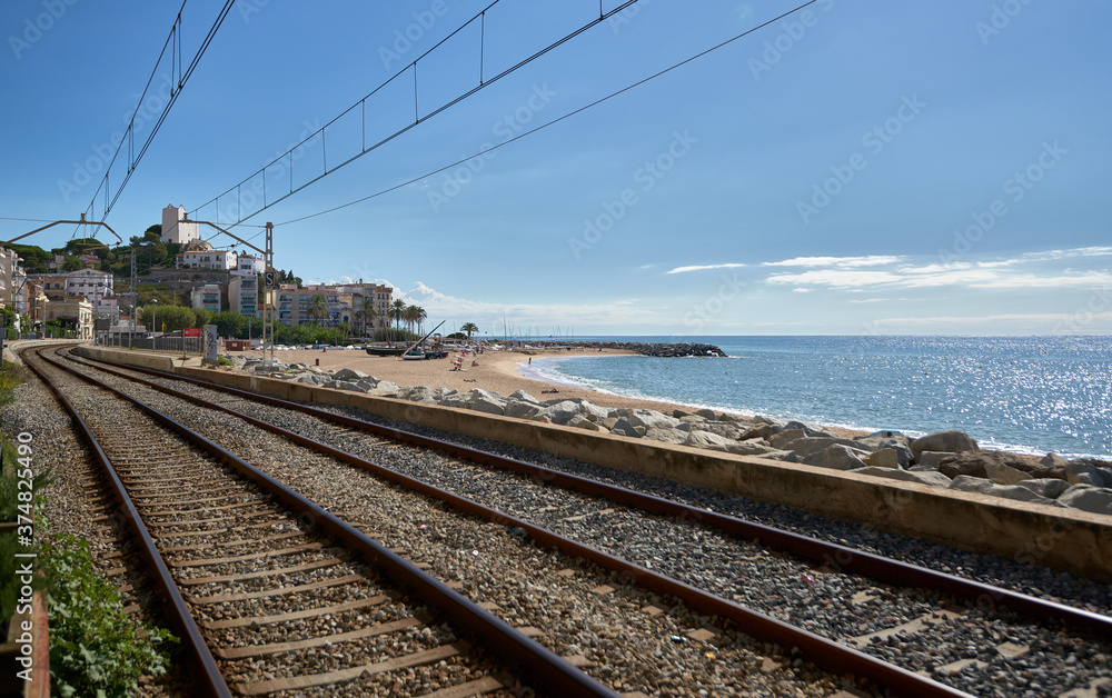 Rail way through a beach to a town with the coast next to it