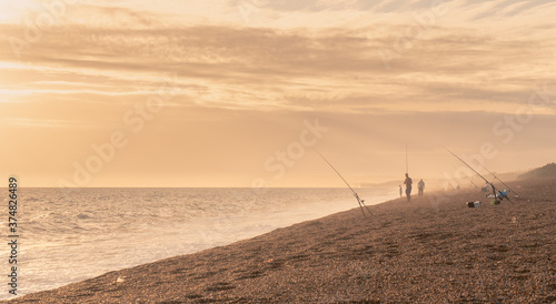 Sunset beach landscape photo with the crashing waves and the sea fishermen on Chisel Beach on the English south coast. This is also known as the Jurassic Coastline.