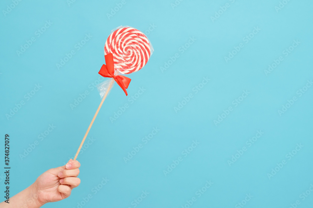 candy cane in hand on blue background candy cane in hand on blue background