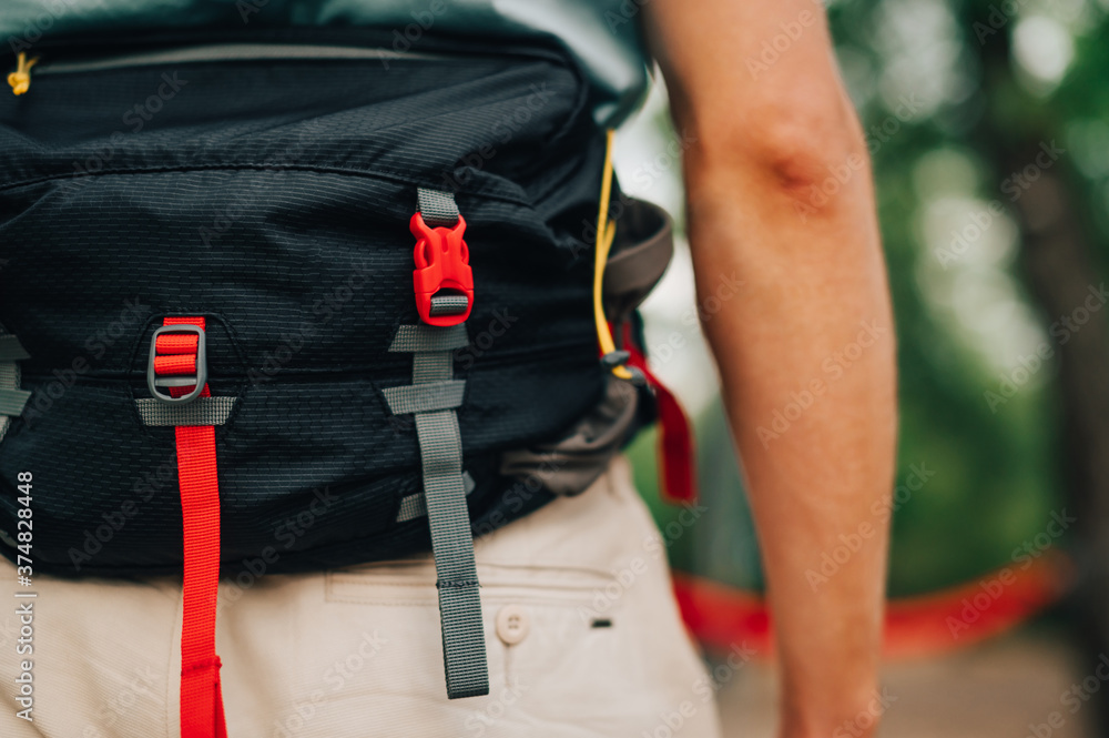 Close-up, cropped photo. Waist bag for travel on the belt of a man on a background of blurred background in the woods Close-up, cropped photo. Waist bag for travel on the belt of a man on a background of blurred background in the woods