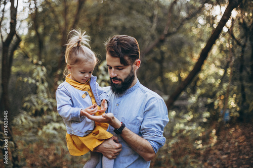 young, stylish bearded father walking with his little daughter in nature at sunset. Family photos of father and one child. selective focus, noise effect © Ananass