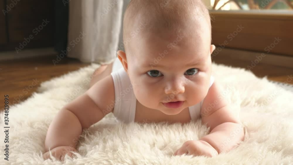 infant toddler happy cute little child lying on belly smiling to camera infant toddler happy cute little child lying on belly smiling to camera