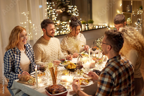 holidays  celebration and people concept - happy smiling friends having christmas dinner party at home in evening