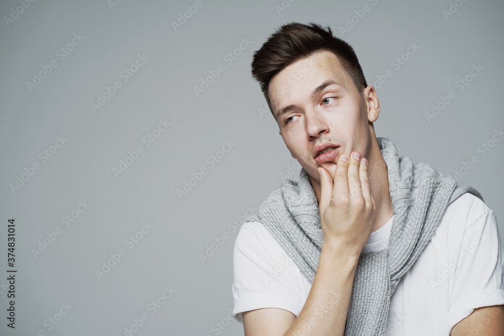 thought tired of work hands touch the face of a young man of European appearance, thinks what to do next. look away. stylish barbershop hairstyle thought tired of work hands touch the face of a young man of European appearance, thinks what to do next. look away. stylish barbershop hairstyle