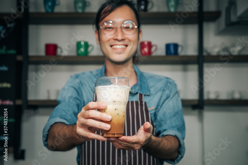 Business woner man coffee shop owner serving ice coffee young entrepreneur,friendly waitor with glasses smiling holding and serving. photo