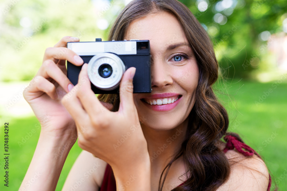 photography, leisure and people concept - happy smiling woman with film camera photographing at summer park photography, leisure and people concept - happy smiling woman with film camera photographing at summer park