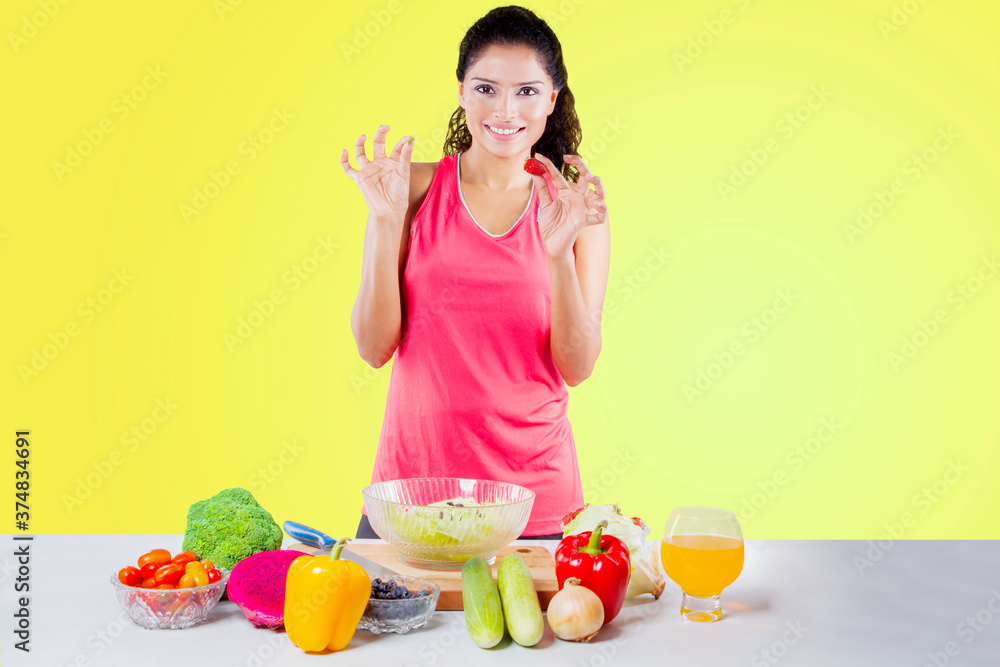 Happy woman hold a strawberry while show OK sign Happy woman hold a strawberry while show OK sign