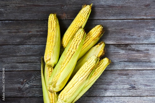Fresh corn on a wooden background. Space for text, top view. Harvest concept