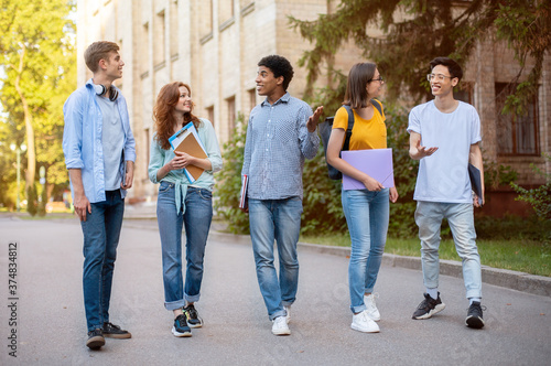 Group Of Multicultural First-Year Students Walking Near University Building Outside