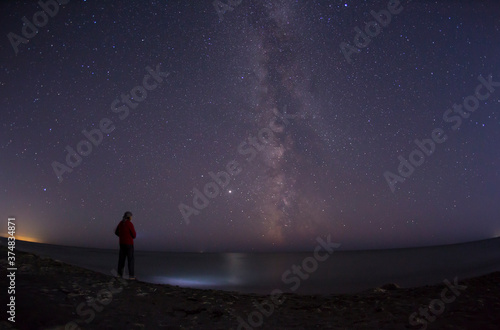 A man stands by the sea and looks at the milky way in a starry night