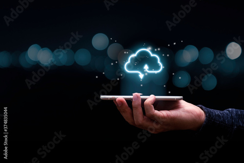 Businessman holding mobile phone with virtual cloud computing to transfer data information and upload download application. Technology transformation concept. photo