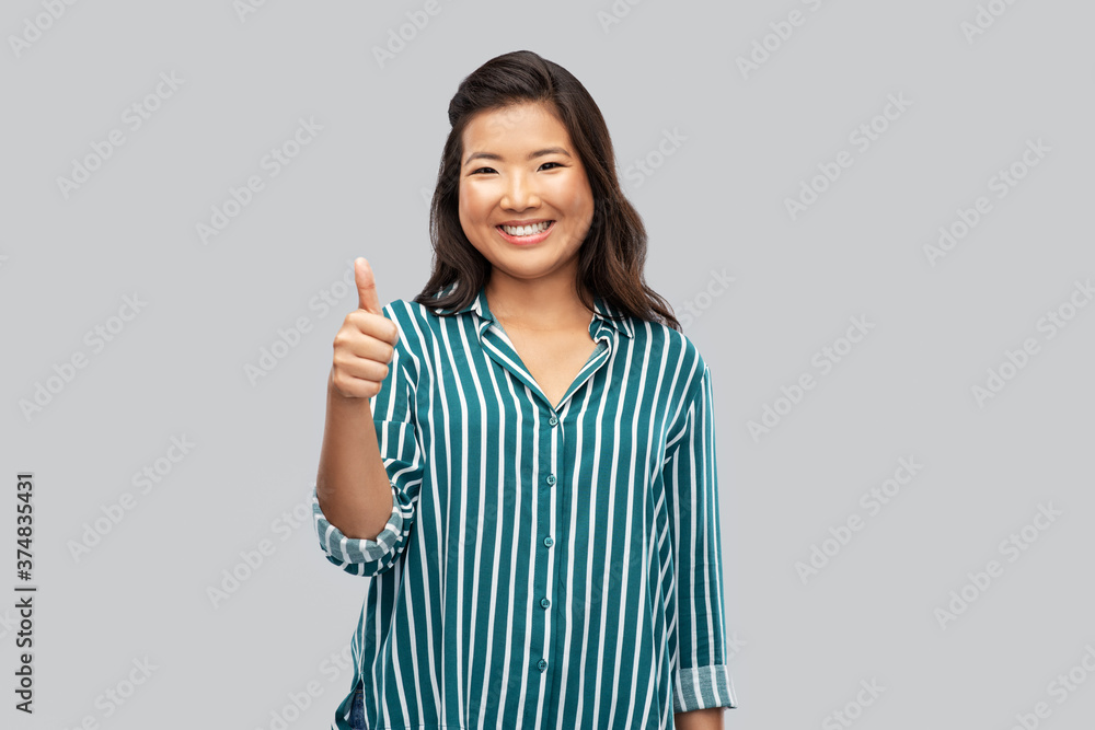 people, gesture and portrait concept - happy asian young woman showing thumbs up over grey background people, gesture and portrait concept - happy asian young woman showing thumbs up over grey background