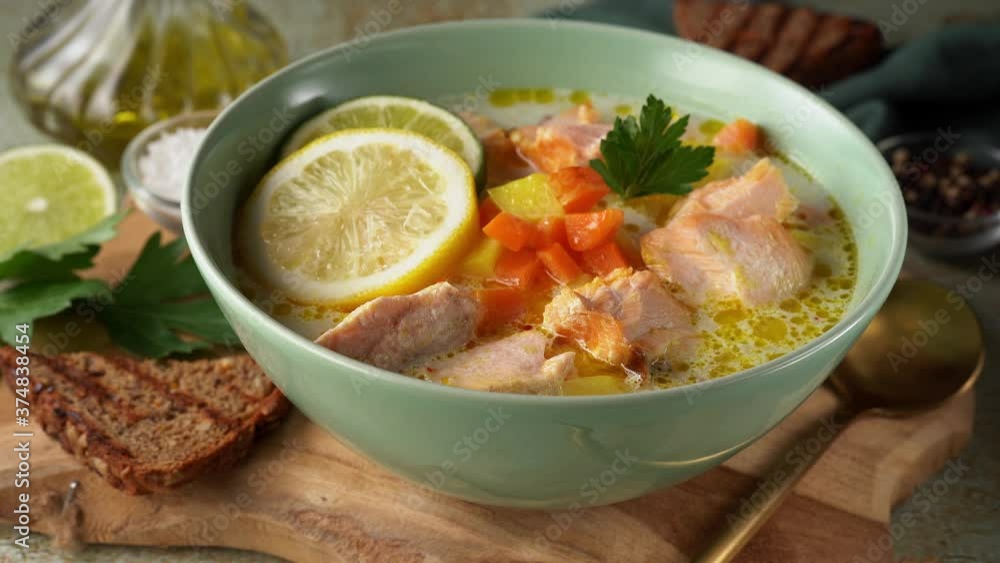 Woman hand placing a plate with healthy salmon fish soup on wooden board. 4K UHD Woman hand placing a plate with healthy salmon fish soup on wooden board. 4K UHD