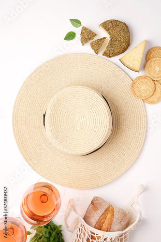 Picnic with rose wine and food. White background with cheese  bread and straw hat. Empty space  food frame