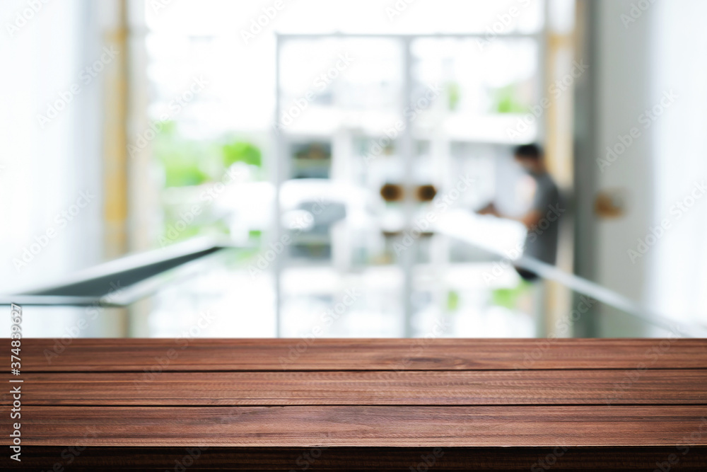 Empty wooden desk space and blurry background of home window for product display montage.