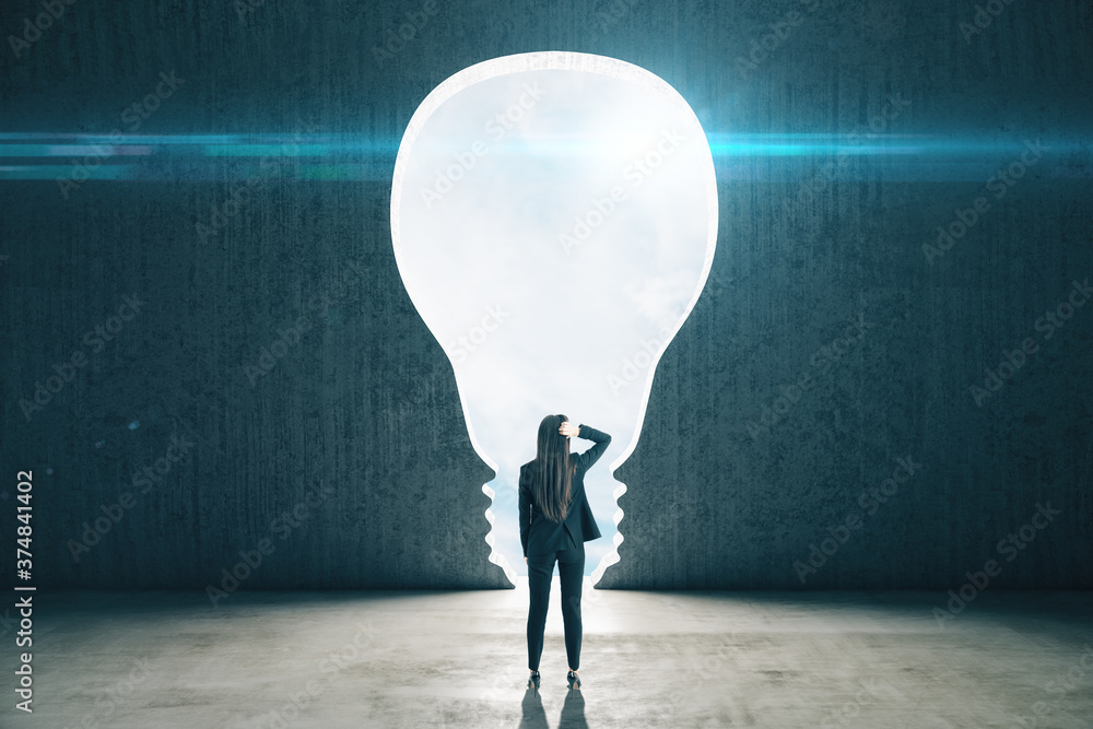 Obraz premium Businesswoman in concrete interior with light bulb window and sky view.