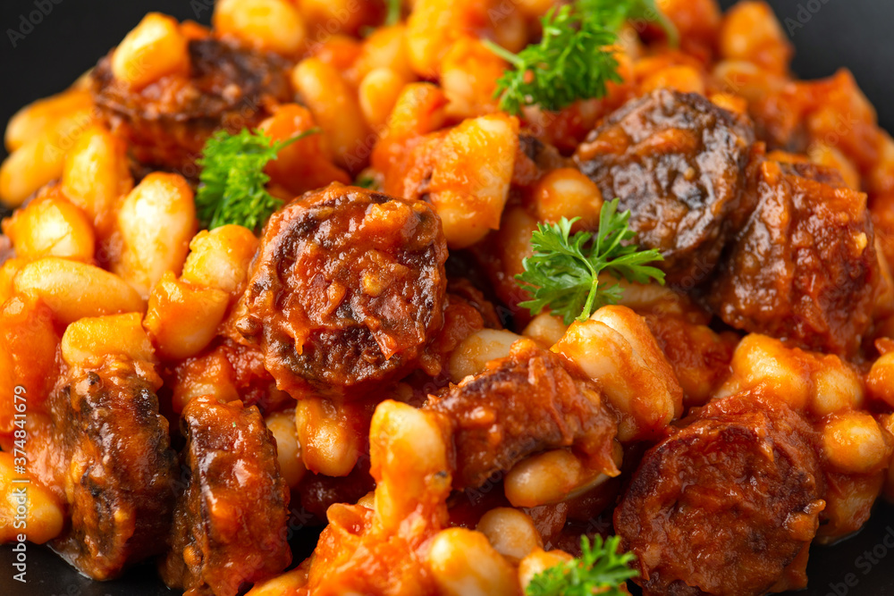 Bean and chorizo stew served in black plate with parsley Bean and chorizo stew served in black plate with parsley