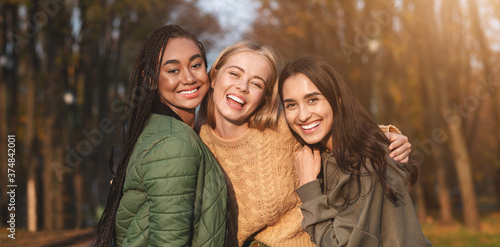 Portrait of three young girlfriends spending time in park photo
