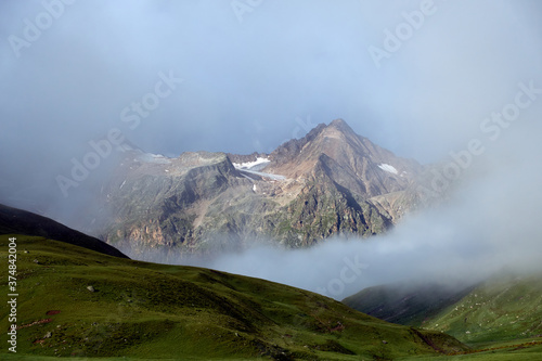 Green valley and mountains in the fog. Green hills in a mountain landscape with light rays passing through the clouds. Caucasus, Russia.