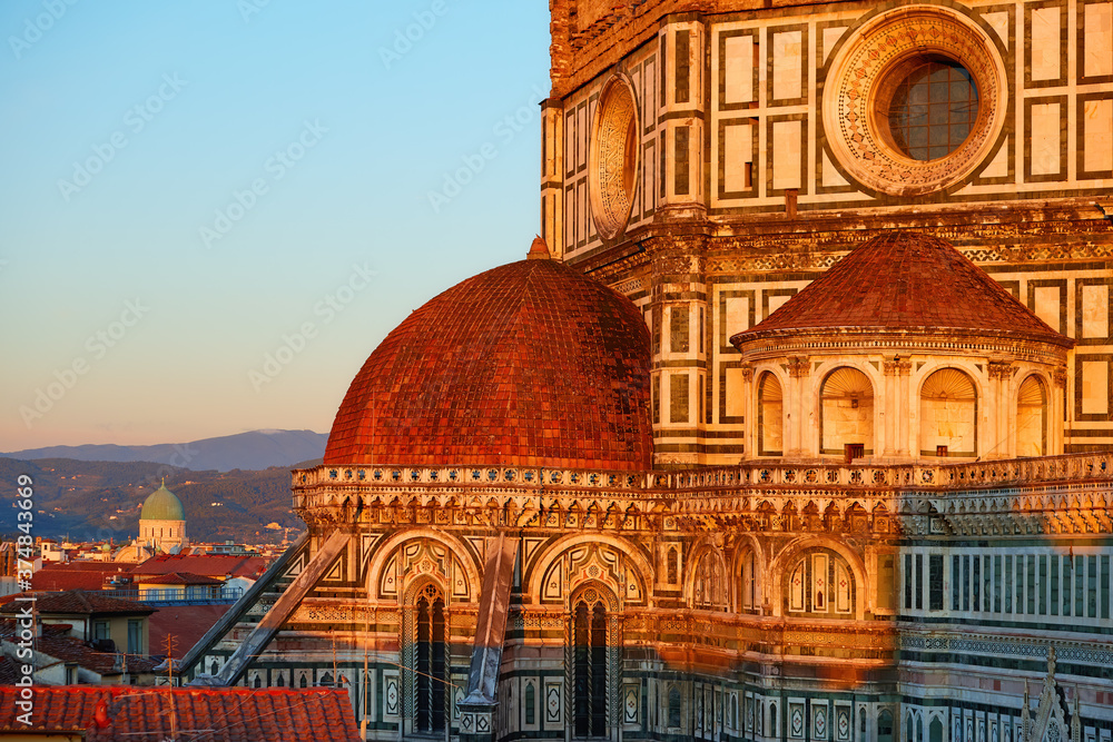 Cathedral of Saint Mary of the Flower in Florence. Tourist hotspot in Tuscany. Aerial view of a gothic dome and medieval city in background, illuminated by setting sun. UNESCO World Heritage Site.