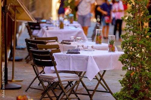 Fototapeta Naklejka Na Ścianę i Meble -  Summer vacation in Tuscany. Tables decorated on a white tablecloth on the street waiting for guests. Pienza, Italy