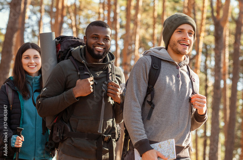 International group of backpackers going by forest