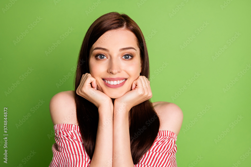 Photo of cute charming teenager girl look camera hands hold chin beaming smiling imagine boyfriend wear striped white red shirt uncovered shoulders bright green color background Photo of cute charming teenager girl look camera hands hold chin beaming smiling imagine boyfriend wear striped white red shirt uncovered shoulders bright green color background