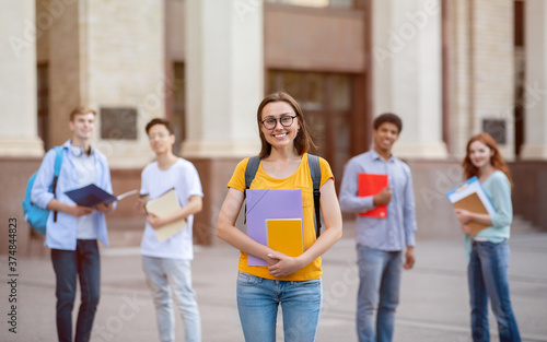 Student Girl Standing Near University Building Outdoors, Posing With Backpack