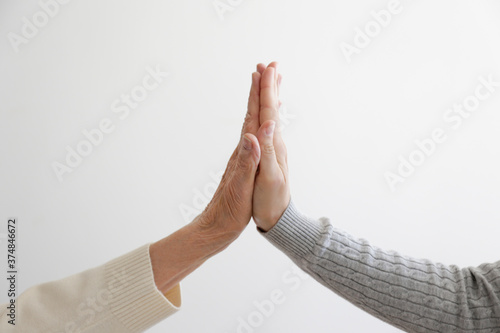 Fotografie Two women of different age high fiving over white wall background