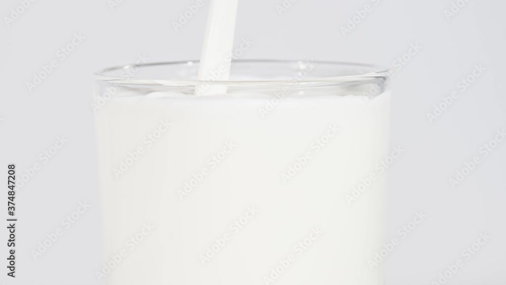 Close up pouring fresh milk in glass over white Close up pouring fresh milk in glass over white