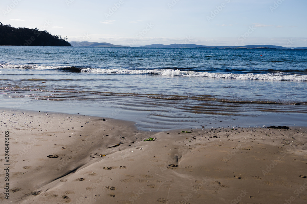 pristine beach in Tasmania with deep blue ocean and dark golden sand