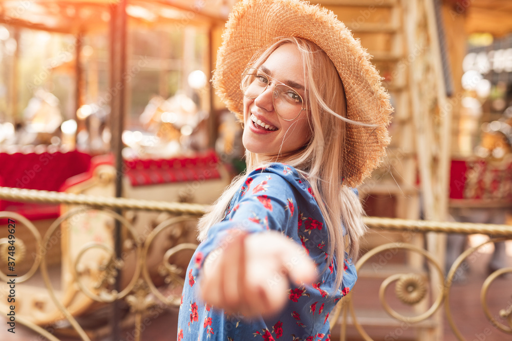 Cheerful woman stretching out arm near merry go round