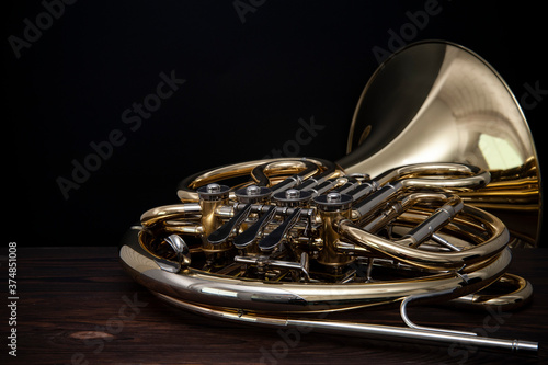 Musical instrument, French horn on a wooden surface on a black background