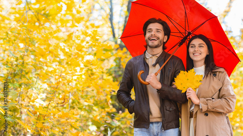 Happy ouple walking under umbrella at rainy autumn day photo