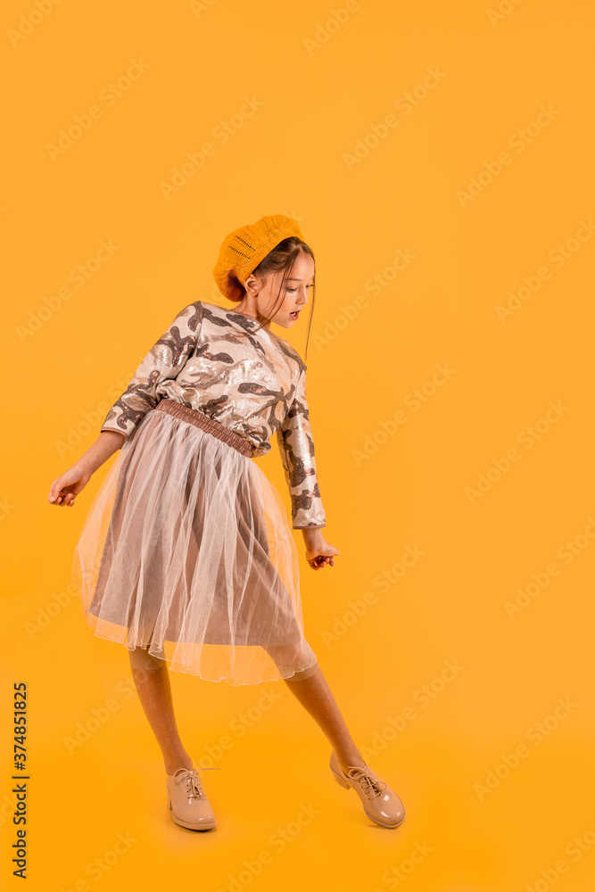 beautiful caucasian girl in stylish school uniform looking down. full length. isolated on yellow background