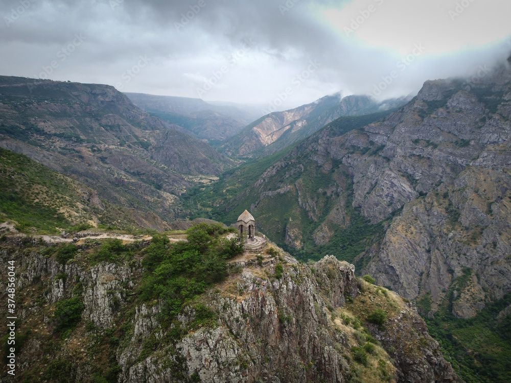Aerial Drone view of Small chapel in the top of the mountain, surrounded by high mountain range, tourists walks around
