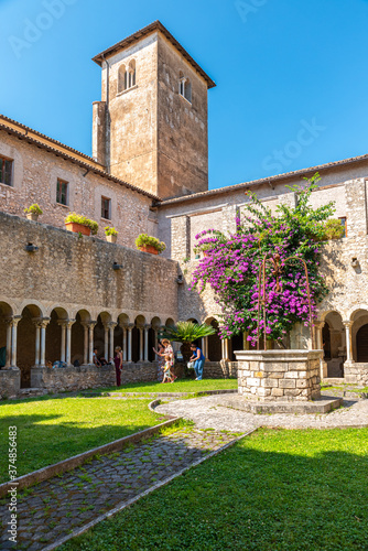 Sermoneta, Italy. June 28th, 2020. Valvisciolo Abbey. Internal cloister with wonderful bougainvillea bloom and strolling visitors. photo