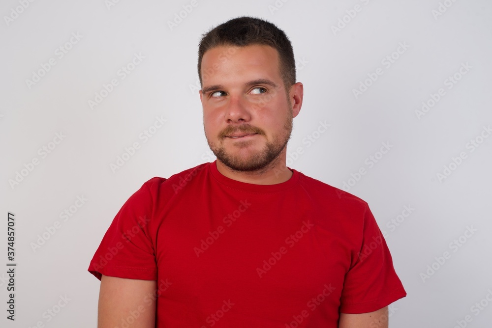 custom made wallpaper toronto digitalPhoto of amazed Young caucasian man wearing red t-shirt over white background bitting lip and looking up to empty space,