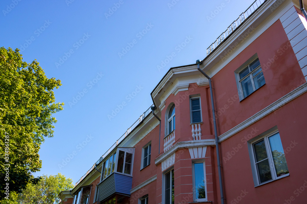 The facade of a pink house against the sky and trees