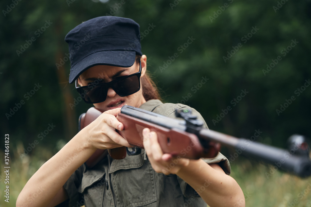 Fototapeta premium Woman soldier Aiming target hunting green leaves 